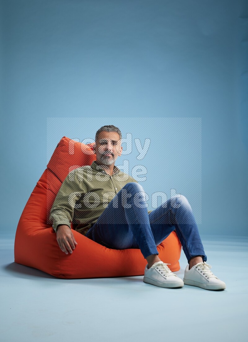 A man sitting on an orange beanbag and interacting with the camera