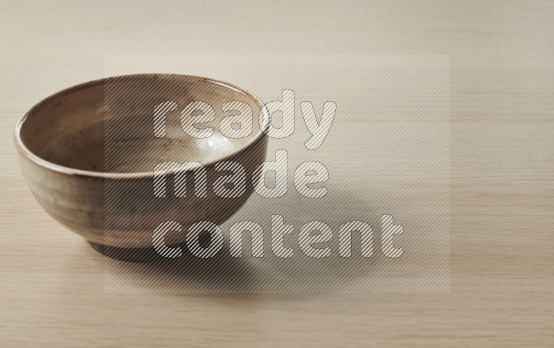 A beige pottery bowl on light wooden background