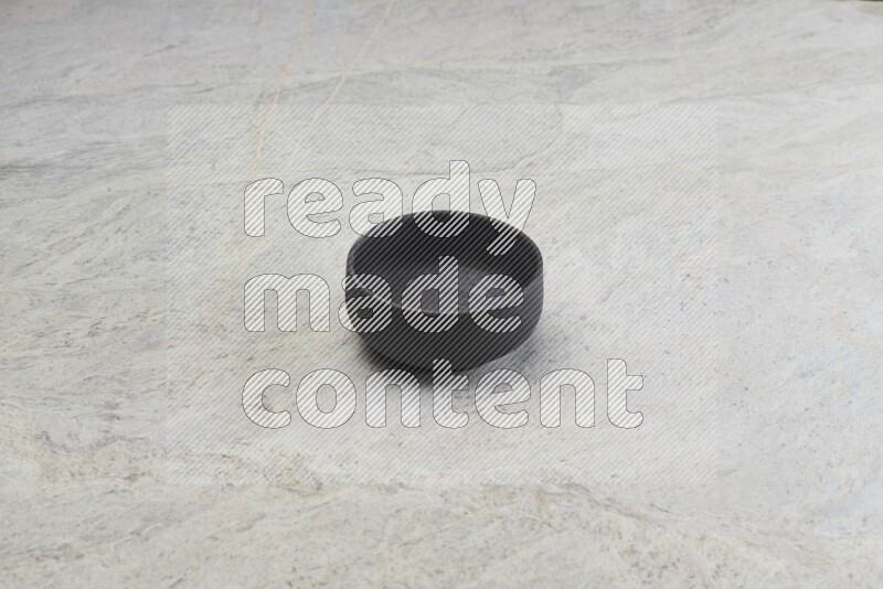 A black pottery bowl on grey marble background