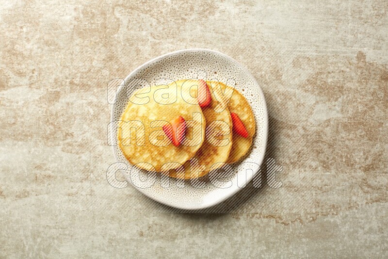 Three stacked strawberry pancakes in an irregular plate on beige background