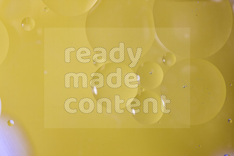 Close-ups of abstract oil bubbles on water surface in shades of yellow