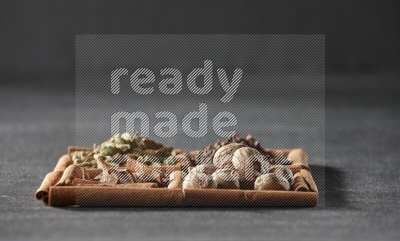 4 squares of cinnamon sticks full of cinnamon, cardamom, cloves and nutmegs on black flooring