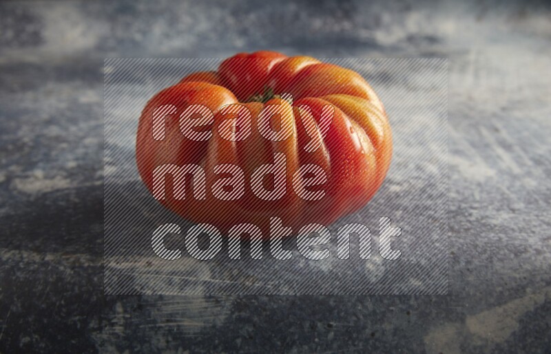 45 degree single heirloom tomato on a textured rustic blue background