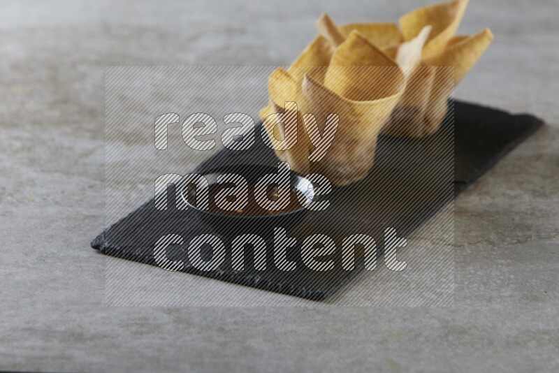 wonton cups with soy sauce ramkin on rectangle slate on grey textured counter top