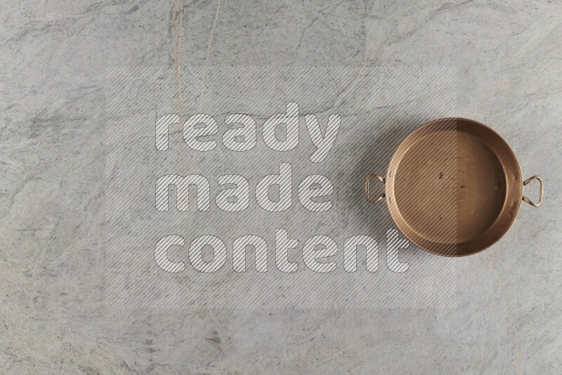 A small copper pan on grey marble background