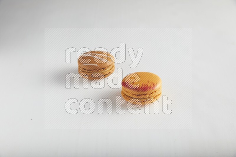 45º Shot of of two assorted Brown Irish Cream, and Orange Exotic macarons on white background