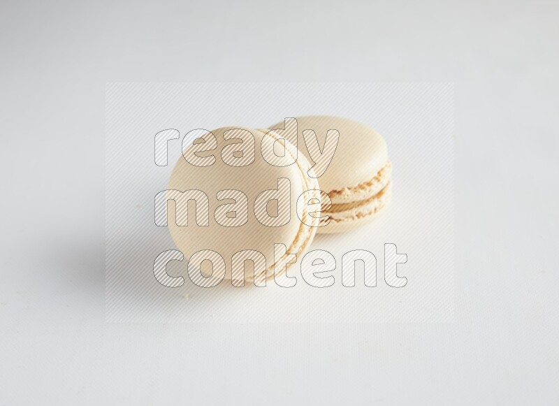 45º Shot of two White Caramel fleur de sel macarons on white background