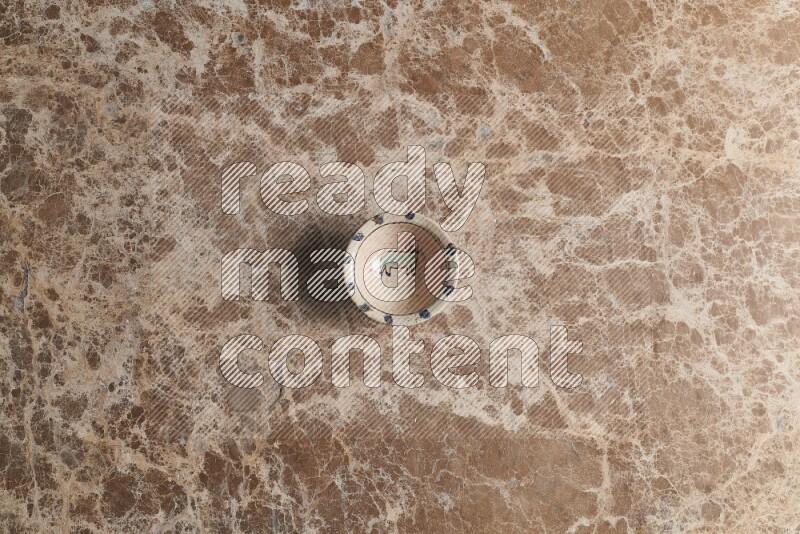 A multicolored pottery bowl on beige marble background