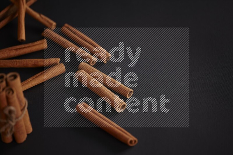Cinnamon sticks stacked on black flooring
