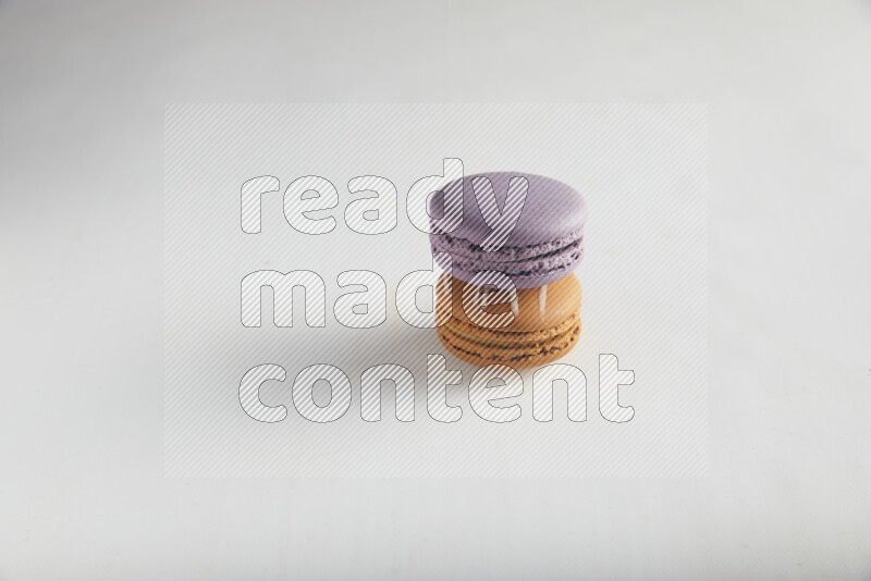 45º Shot of of two assorted Brown Irish Cream, and Purple Blueberry macarons on white background