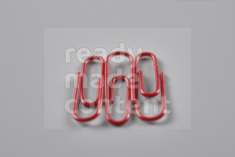 Red paper clips isolated on a grey background