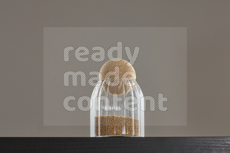 Mustard seeds in a glass jar on black background
