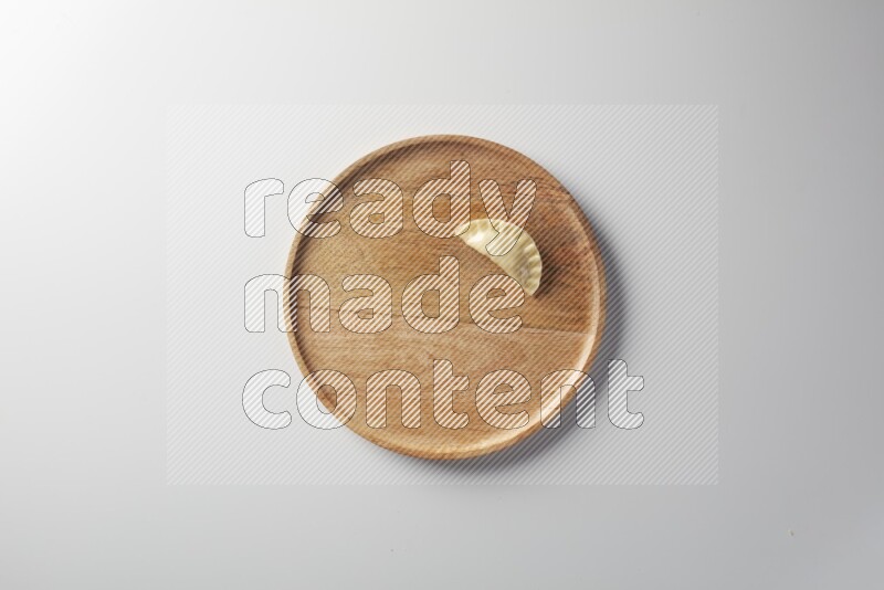 A single Sambosa on a wooden round plate on a white background
