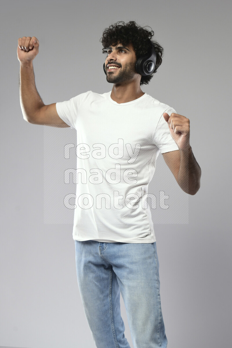 A man wearing casual standing and putting on headphones on white background