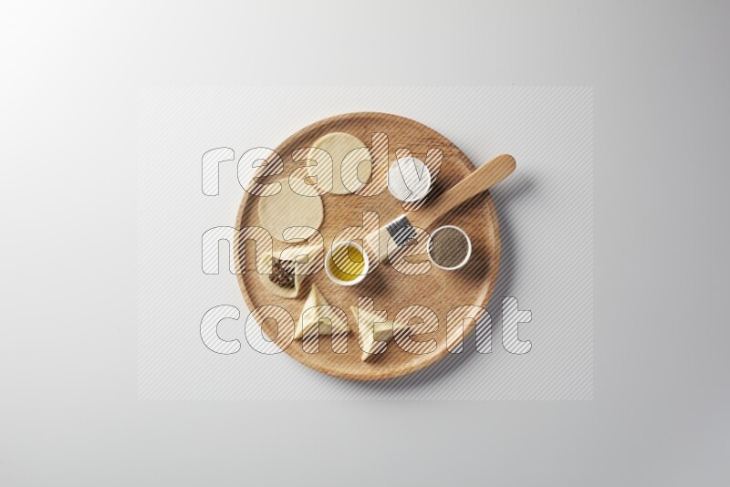 two closed sambosas and one open sambosa filled with meat while salt, black pepper and oil with oil brush aside in a wooden dish on a white background