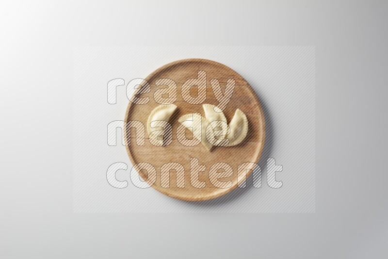 Four Sambosas on a wooden round plate on a white background