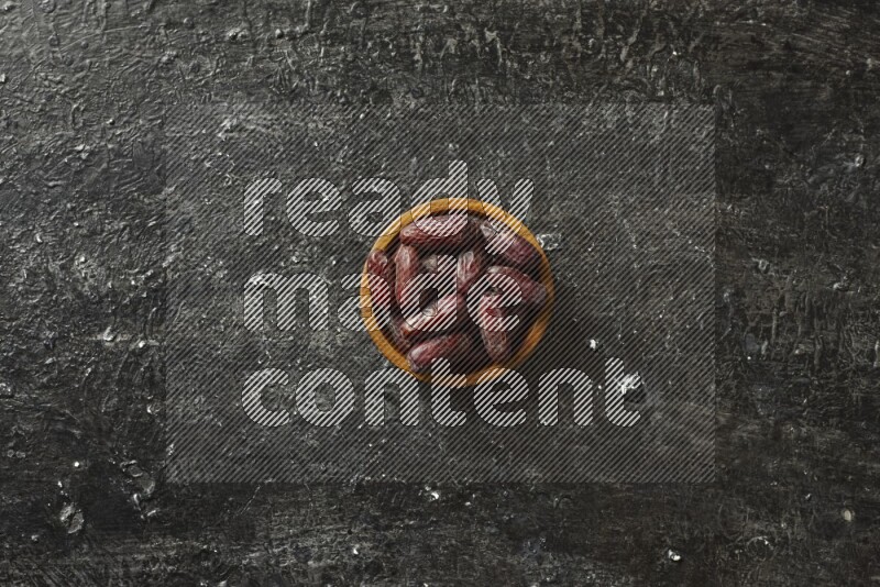 Dates in wooden bowls in a dark setup