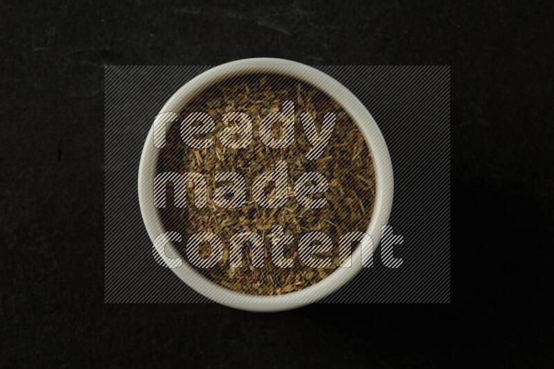 white ceramic round sauce bowl filled with herbs on grey textured countertop