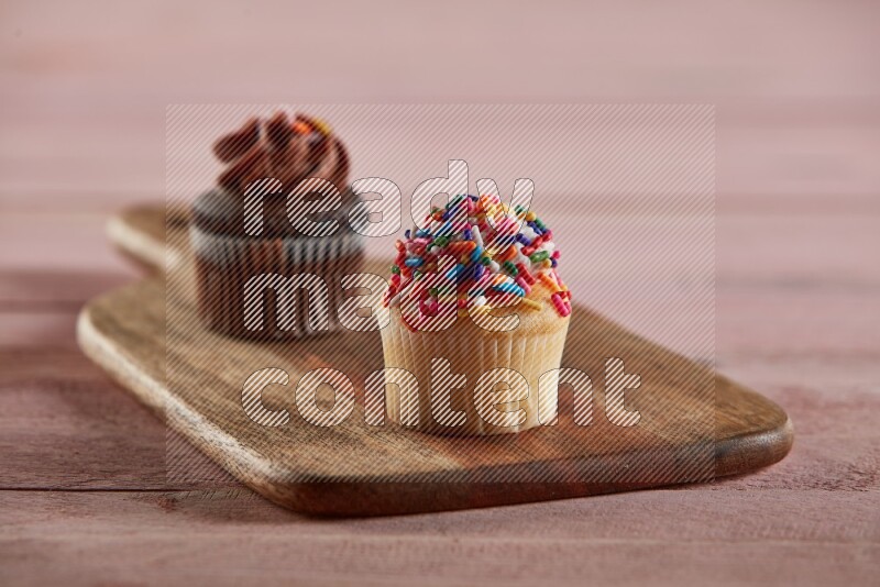 Vanilla mini cupcake topped with sprinkles on a wooden board