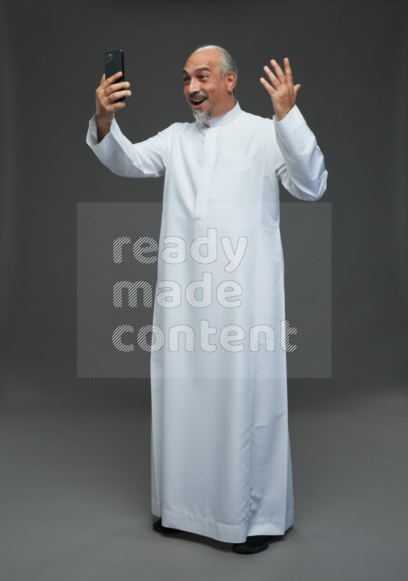 Saudi man without shomag Standing taking selfie on gray background