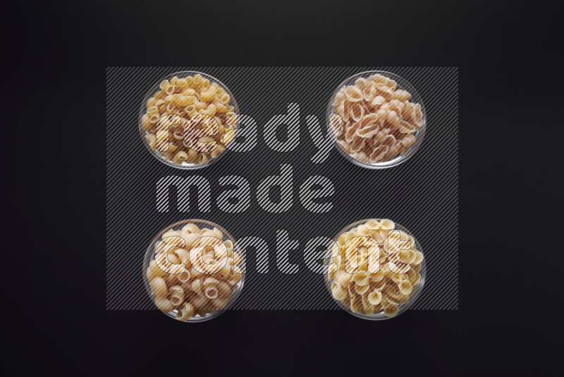 أنواع مختلفة من المعكرونة في وعاء زجاجي علي خلفية سوداء