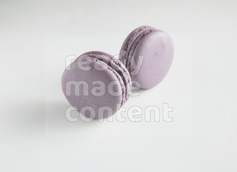 45º Shot of two Purple Blueberry macarons on white background