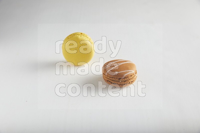 45º Shot of of two assorted Brown Irish Cream, and Yellow Lemon macarons on white background