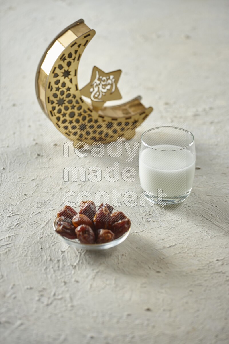 A wooden golden crescent lantern with different drinks, dates, nuts, prayer beads and quran on white background