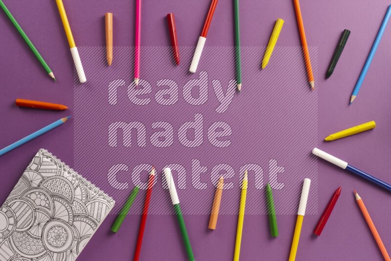 A coloring book with coloring pens on purple background