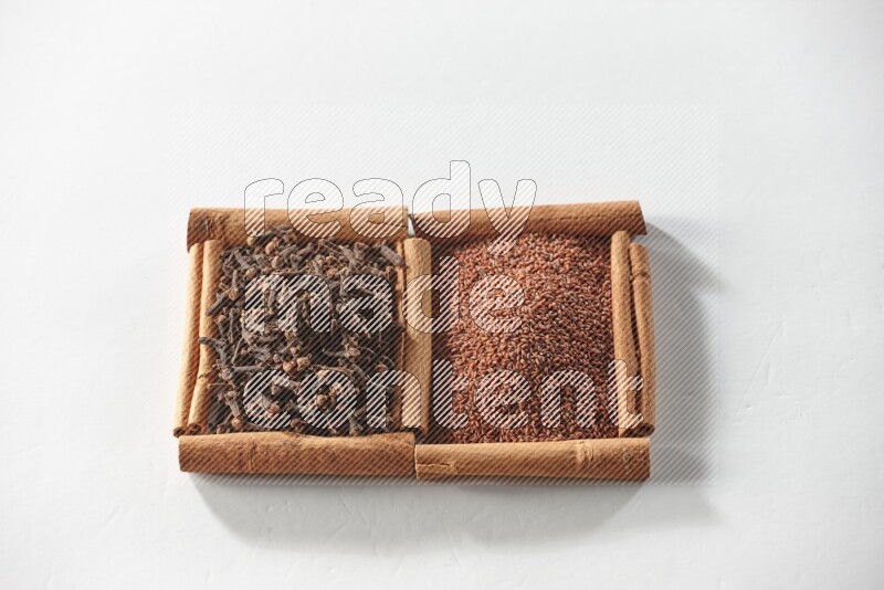 2 squares of cinnamon sticks full of garden cress and cloves on white flooring