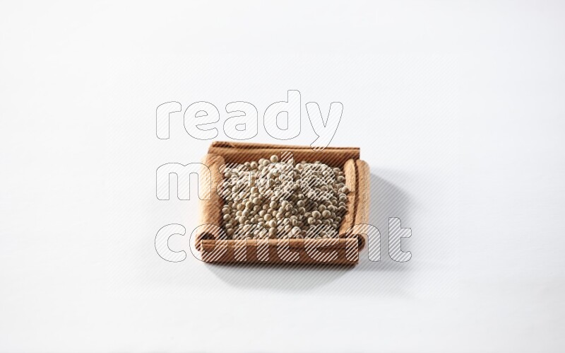A single square of cinnamon sticks full of white pepper on white flooring