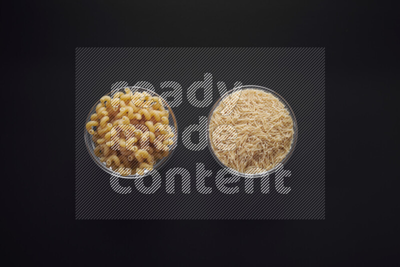 Different pasta types in glass bowls on black background