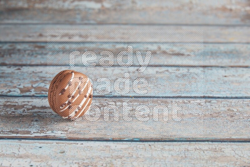 45º Shot of Brown white Chocolate Caramel macaron on light blue wooden background