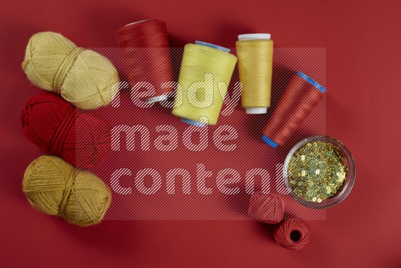 A yellow collection of sewing and tailoring tools arranged on a red background