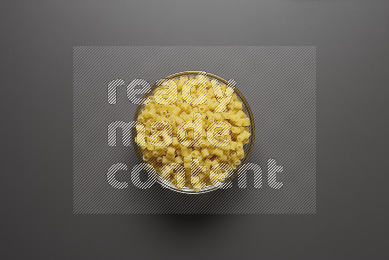 Small rings pasta in a glass bowl on grey background