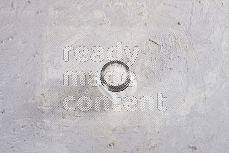 A glass jar full of coarse sea salt crystals on white background