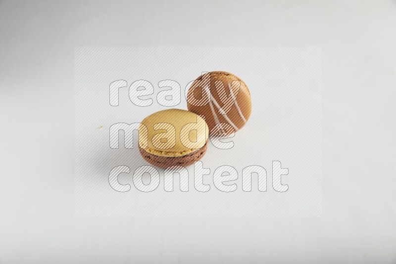 45º Shot of of two assorted Brown Irish Cream, and Yellow, and Brown Chai Latte macarons on white background