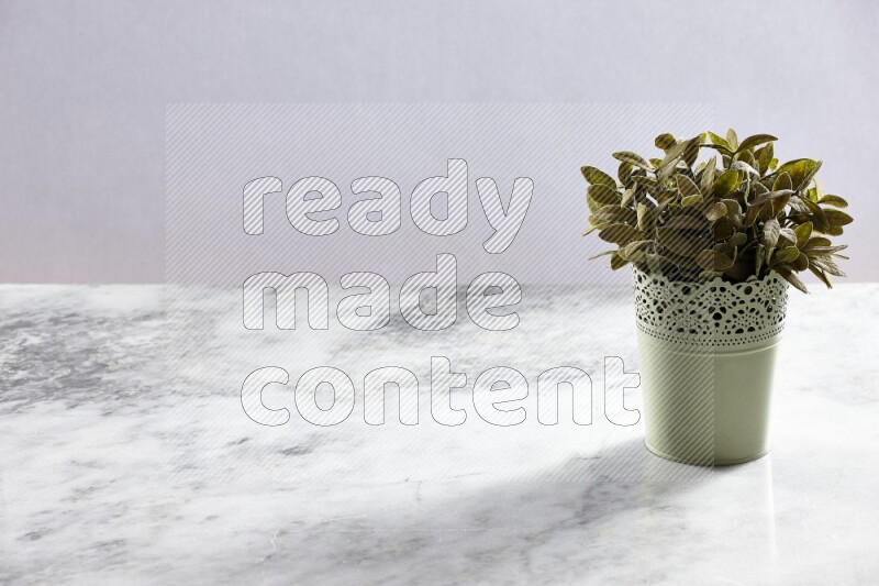 Artificial plant in green decorative pot on grey marble background