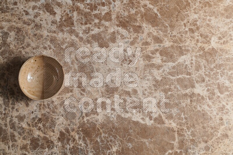 A beige pottery bowl on beige marble background