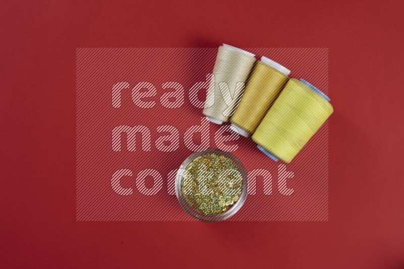 A yellow collection of sewing and tailoring tools arranged on a red background