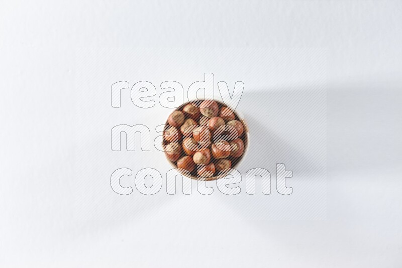 A beige ceramic bowl full of hazelnuts on a white background in different angles