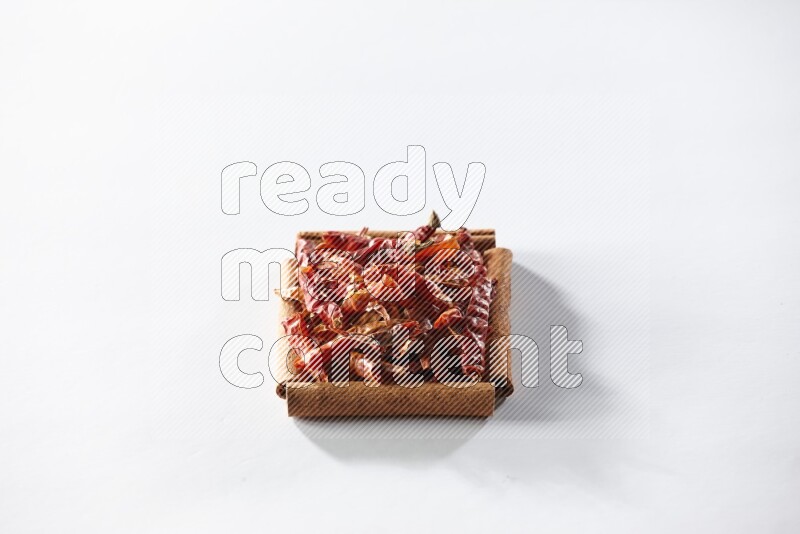 A single square of cinnamon sticks full of chilis on white flooring
