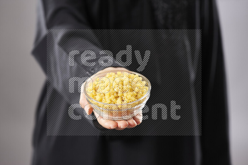 Woman in abaya holding different kinds of pasta in different positions