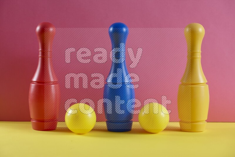 Plastic bowling pins with balls on pink and yellow background (kids toys)