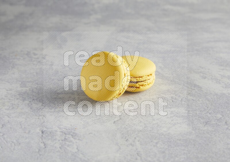 45º Shot of two Yellow Lemon macarons  on white  marble background