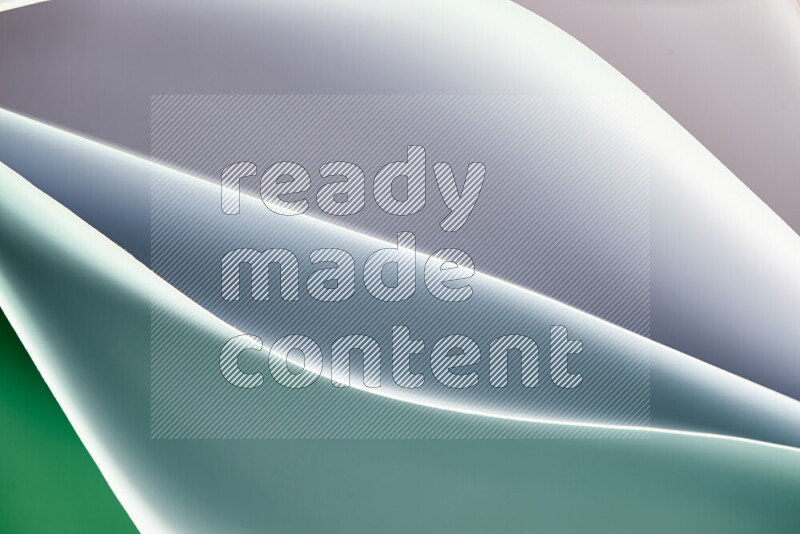 هذه الصورة تعرض تكوين فن الورق التجريدي مع منحنيات ورقية بتدرجات اللون الأخضر والأبيض المكونه بواسطة الضوء الملون