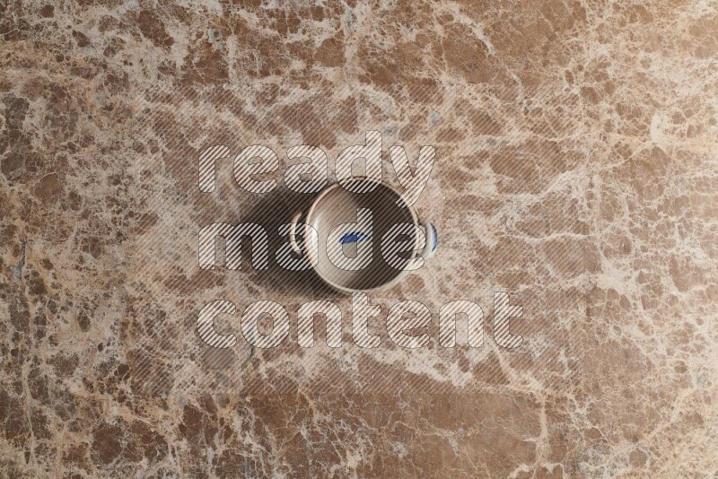 A multicolored pottery bowl on beige marble background