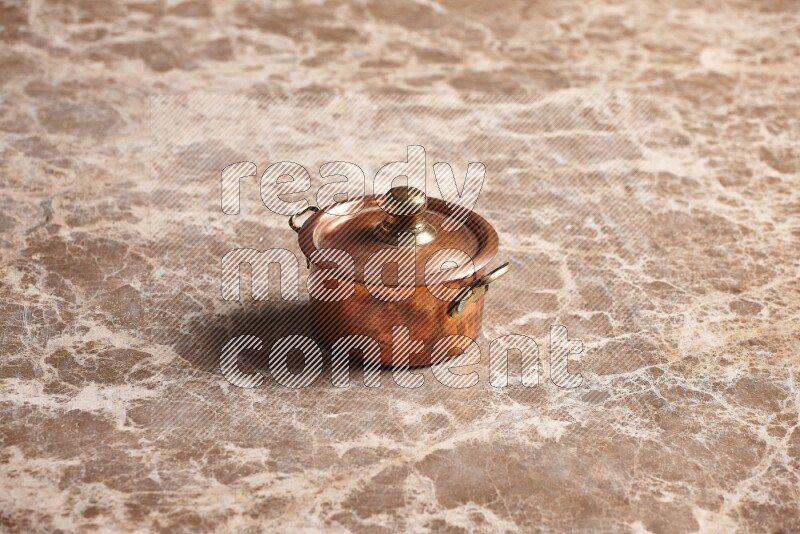 A small copper pot on beige marble background