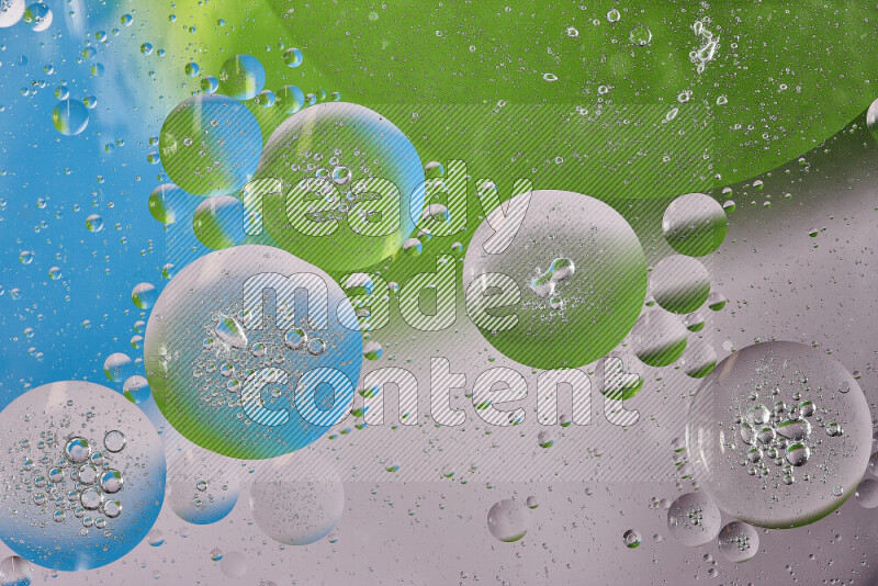 Close-ups of abstract oil bubbles on water surface in shades of white, green and blue