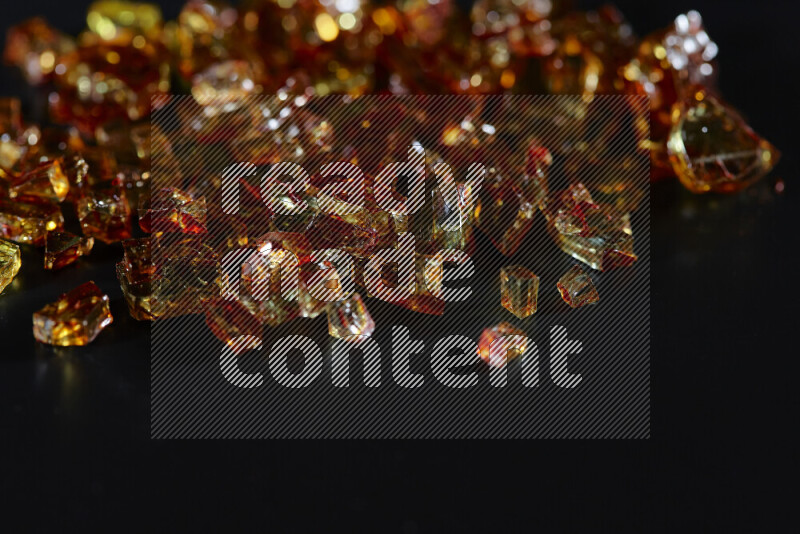 Transparent orange fragments of glass scattered on a black background